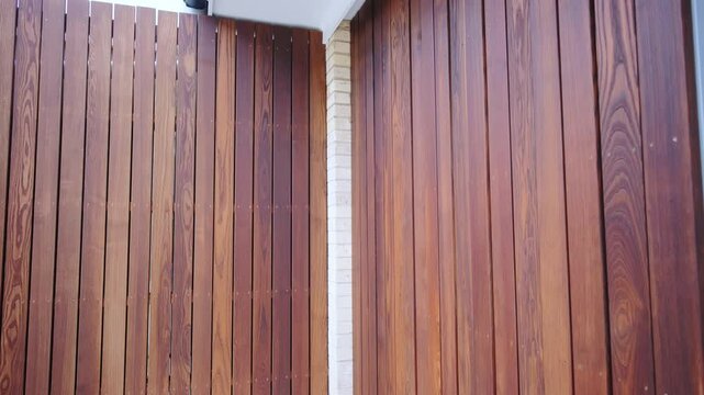 Vertical wooden panels in dark brown color for creative decoration of external wall. 