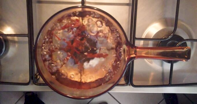 Cenital shot of water with cinnamon on the stove just about to boil, as part of the routine for preparing tea or coffee for breakfast