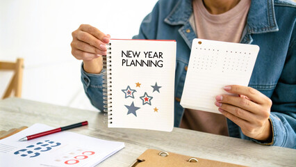 person holding a card and paper with text and symbols representing new year planning