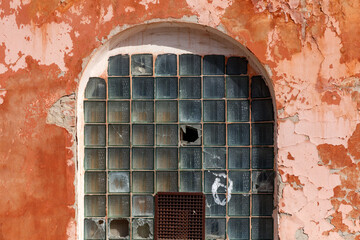 A window with a hole in it and a piece of graffiti on the wall