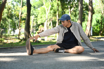Obraz premium Young sporty man stretching outdoors before running in nature during sunny summer day