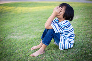 A sad little girl sitting alone outside