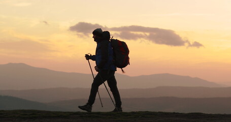 Silhouette of a traveler walking on a mountain slope against the background of majestic mountains....