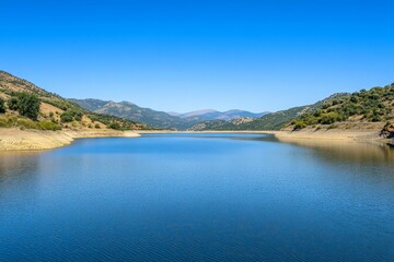 Fototapeta premium Blue lake between green hills under blue sky.