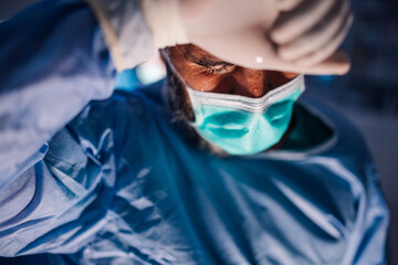 Focused Surgeon Adjusting Mask Under Bright Operating Room Lights