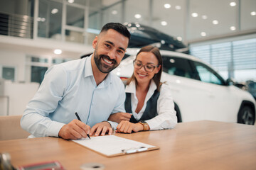 Couple poses with signed contract, celebrating new car deal.