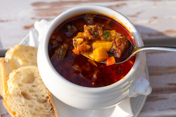 Traditional Hungarian food. Beef goulash soup. Travel to Budapest for its cuisine. Food photography of two bowls with beef goulash soup on a wooden table in a restaurant.