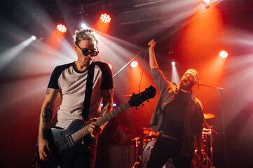 Rock band performing live on stage with energetic singer and guitarist