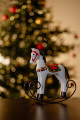 Children's toy wooden horse Against the background of a Christmas tree with lights on