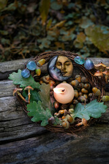 burning candle, moon amulet, crystals, acorns, oak leaves on tree trunk outdoor, nature abstract...