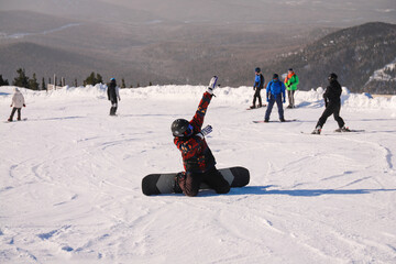 snowboarder sitting on his knees in the middle of a snowy slope