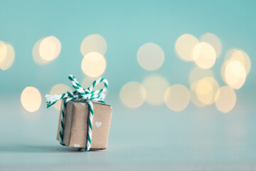 Cute little gift box against blurred festive light background.