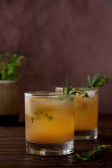 Pear drink cocktail with lemon, rosemary, thyme and ice on a wooden table. Healthy drink, sugar and alcohol free. Vertical orientation.