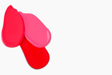 Composition of red lipstick smears in various shades, including dark red, light red, burgundy, and pink, isolated on a light background.