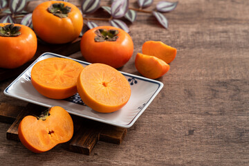Fresh ripe persimmon fruit on wooden table background.