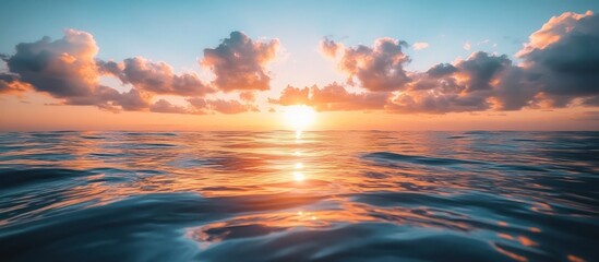 Fototapeta premium A breathtaking sunset over a calm ocean, with the golden sun shining through the clouds, reflecting off the rippling water.