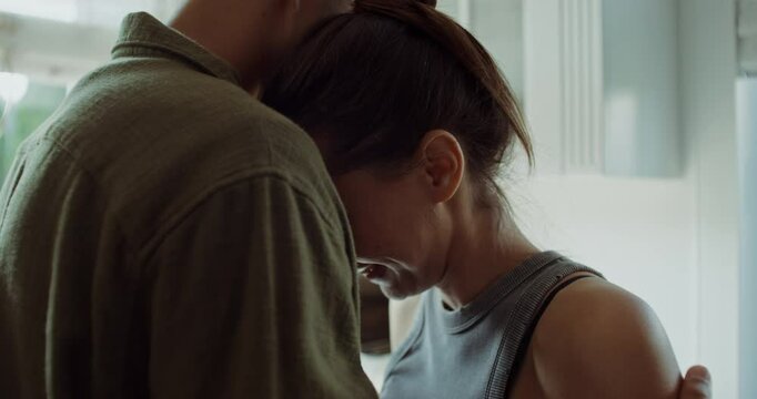 Husband and wife reconcile after a quarrel. They're hugging. The woman is crying. Close-up of her face