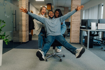 Business team having fun riding office chair in modern office