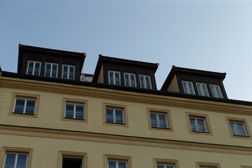 Obraz premium The upper floor windows are adorned with distinctive roofs that contribute to the unique aesthetic of the residential building facade, showcasing a blend of modern design and classic style