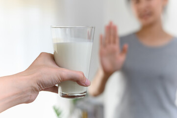 Woman gesturing refusing stop or reject say no glass of milk, Lactose intolerance food allergy and...