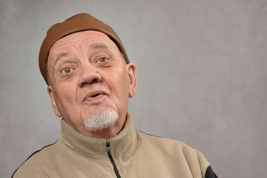 portrait homme s&eacute;nior avec casquette expressif sur fond gris