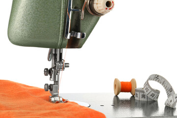 Sewing machine with orange fabric, measuring tape and spool of thread isolated on white