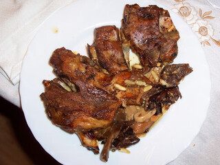Plato de carne asada con hueso, servido sobre un plato blanco, acompañado de champiñones y...