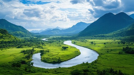 Obraz premium A winding river cutting through a lush valley with distant mountains in the background.