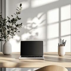 Fototapeta premium minimalist office setup with laptop on wooden desk, accompanied by vase of greenery and cup of pens, bathed in soft natural light