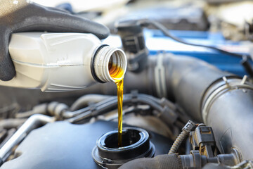 Man pouring motor oil into car engine, closeup