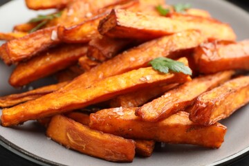 Delicious sweet potato fries with spices on plate, closeup