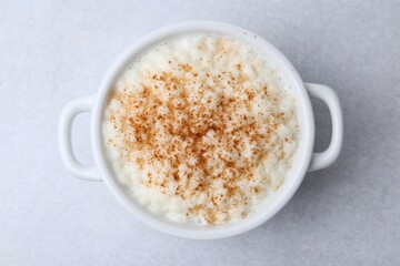 Delicious rice pudding with cinnamon on light table, top view