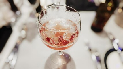 Pink drink with ice in a wine glass on a restaurant table stock footage