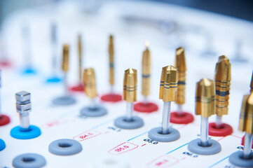 Dental implant surgery tools on a white surface. Close-up of golden drill bits and precision instruments in a medical or dental clinic setting.