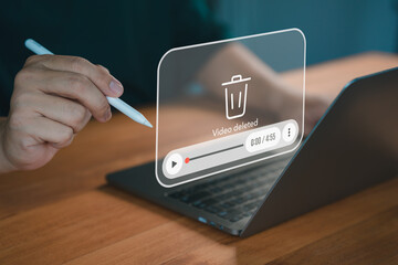 A close-up of a hand using a pen on a laptop with a virtual overlay displaying a "video deleted" message, symbolizing digital file management and deletion.