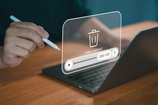 A close-up of a hand using a pen on a laptop with a virtual overlay displaying a "video deleted" message, symbolizing digital file management and deletion.
