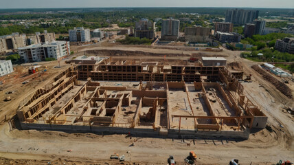 Obraz premium Aerial view of large construction site featuring partially built structure surrounded by urban development. scene captures ongoing progress in city landscape