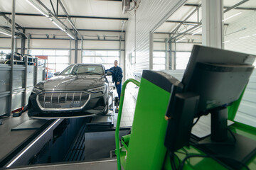 Auto mechanic installing sensor during suspension adjustment and automobile wheel alignment work at repair service station