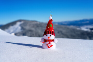 Cute snowman in winter scenery, in the mountains with fresh fluffy snow. Happy Christmas and New Year concept