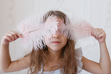 girl holding beautiful feathers in front of her eyes