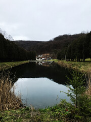 Fototapeta premium Serene countryside view with tranquil pond and rustic houses