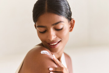 Rejuvenating Skincare Moment. Young Woman Gently Applies Cream On Her Shoulder, Embracing Self-Care...