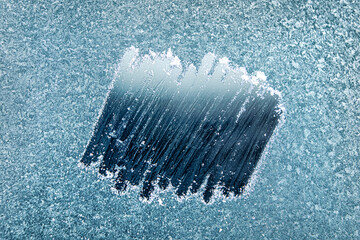 Frosted Window With a Clear Patch Revealing an Icy Blue Background During a Cold Winter Morning