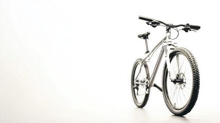Obraz premium A sleek mountain bike with large tires stands against a minimalist white background, emphasizing its modern design and rugged features.