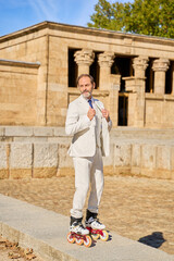 Man in a suit rollerblading near an ancient stone temple outdoors