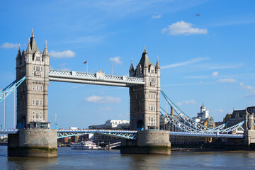 Obraz premium Tower Bridge, an iconic symbol of London, stands majestically over the River Thames under a clear blue sky. This historic landmark, popular tourist destination and a must-see for any visitor to the UK