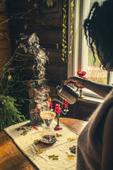 Pour over filter coffee alternative brewing method. Girl is pouring hot water over roasted and ground coffee beans contained in paper filter. Ceramic coffee cups, biscuits and candles. Vintage 