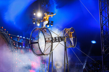Brave male acrobats in the rotating wheel of death perform under the dome of the circus.