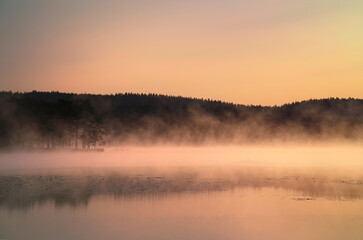 Sunrise with fog forming over a lake in Sweden, at dawn. Romantic silence