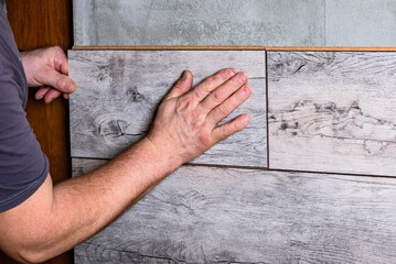 Construction worker laying laminate in living room on wall using glue foam.